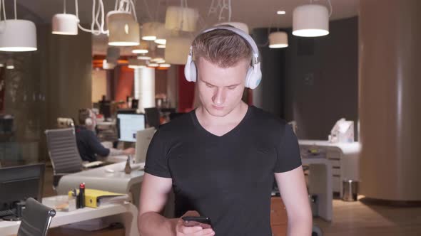 A young European Man Wearing Headphones Listening to Music Late at Night in an Empty Office