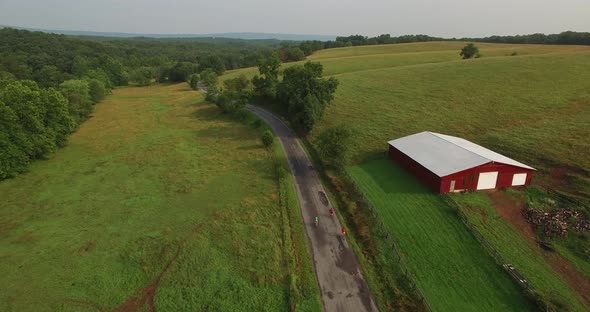 Aerial views of family bicycling along pastoral country roads.