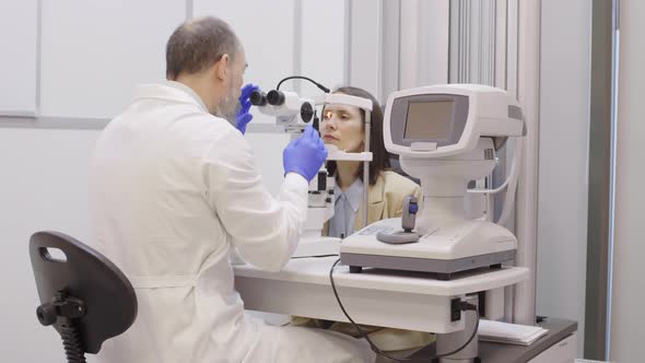 Optometrist Examining Eyes of Woman with Slit Lamp Machine