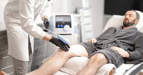 Doctor Doing Magnetic Therapy on Male Knee