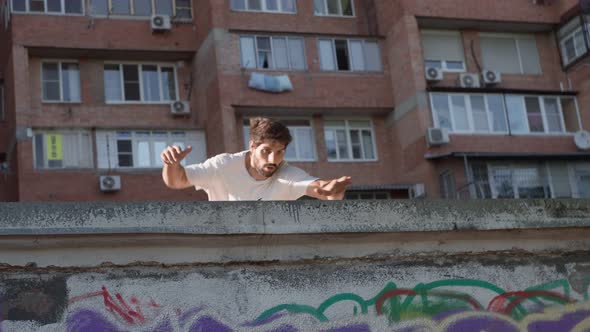 Male Parkour Athlete Performs Somersault Screw Backdrop Building