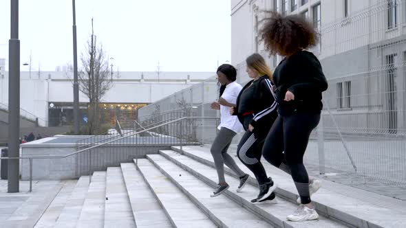 Three sportive young women training in the city