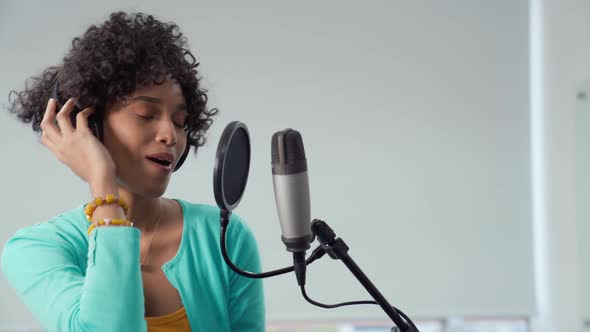 Young African American Pretty Woman Singing in Front of Microphone