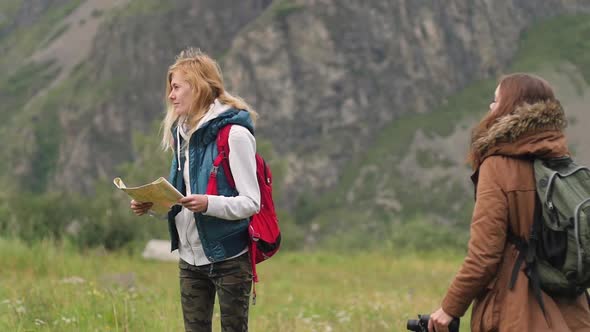 Young Women Travel in the Mountains. Using the Map and Binoculars. Two Friends Travel Together. Two