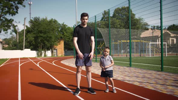 Father and Son in Sportswear are Going to Train Together on the Sports Ground Outside