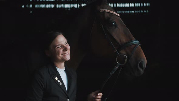 Joyful Girl Laughing And Posing With Her Horse In The Stable Holding Its Rope