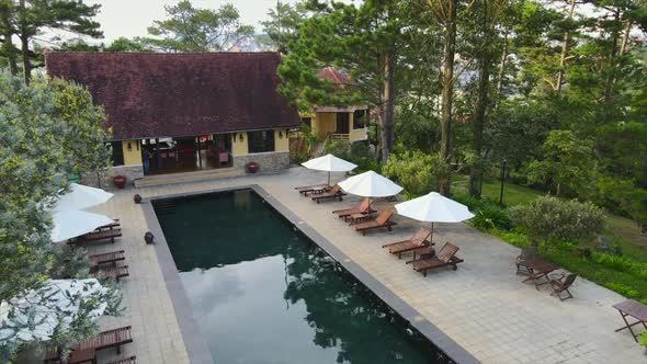 Aerial drone flying above of a beautiful swimming pool under sunshine reveal landscape of resort on