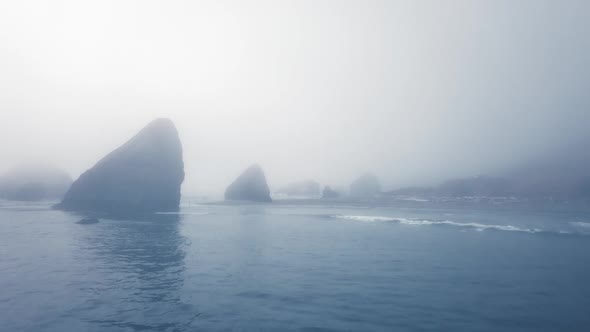 Dronе shot calm ocean near a rocky shore in heavy fog (Ariya's Beach, Oregon, USA)