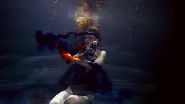 Charming Woman is Swimming Underwater and Playing with Blue and Red Colors Art and Fantasy Shot