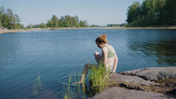 Young Woman in Bikini Steps Into Cold Water Resting By Lake