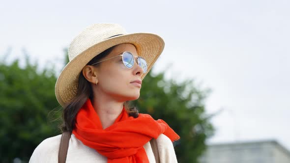 Serious woman with a red scarf looking forward near the bridge