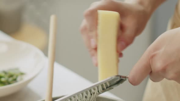 Crop woman grating cheese for pasta