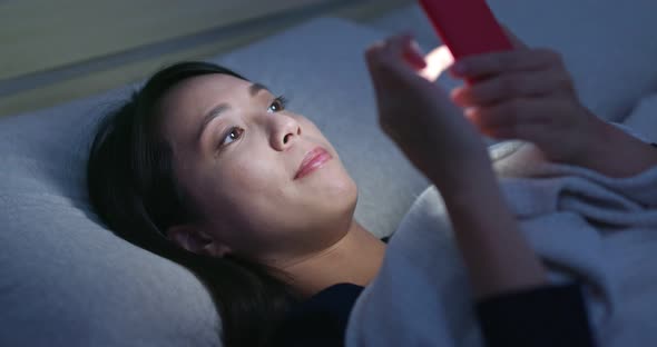 Woman Watch on Mobile Phone and Lying on Bed at Night