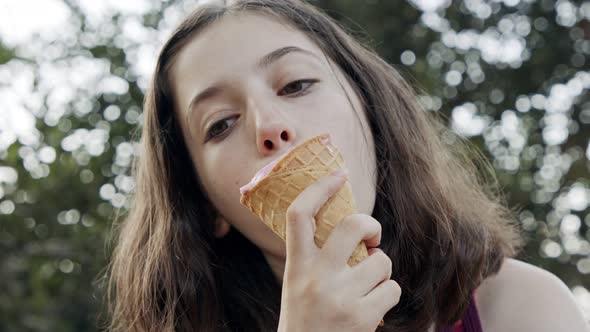 Young girl eating Ice Cream from a cone, enjoying and laughing