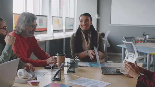 Young Black Woman Speaking to Colleagues at Business Meeting