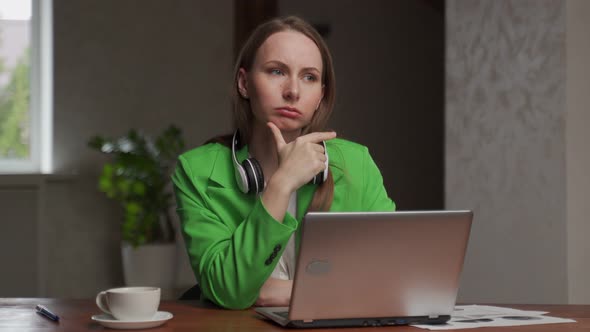 Pensive Woman Sighs Sitting at Table Near Laptop in Office