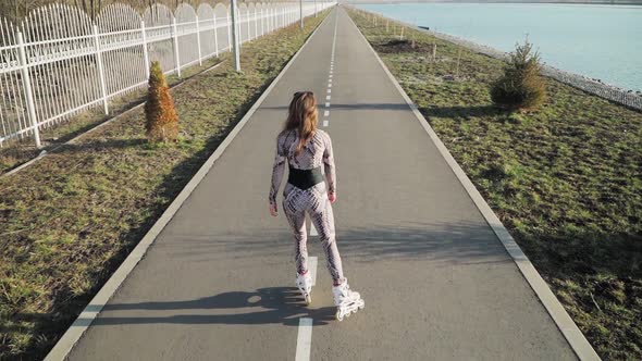 Athletic Slender Girl Rollerblading Path Along Lake