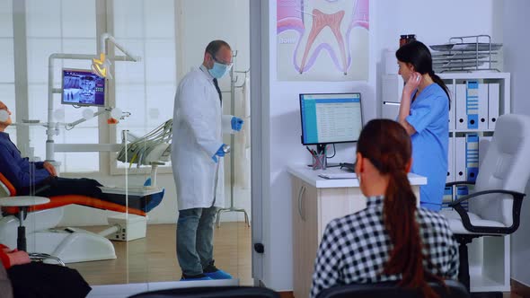 Dentist with Protective Mask Giving Teeth X-ray To Nurse