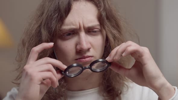 Headshot Portrait of Young Man Taking Off Eyeglasses and Squinting Looking at Camera