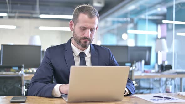 Young Businessman Thinking and Working on Laptop