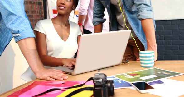 Businesspeople interacting while using laptop