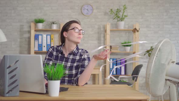 Young Woman Working at Laptop in Office Sitting in Front of Fan