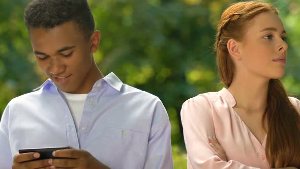 Upset Young Female Offending Mixed-Race Boyfriend Playing Game on Smartphone