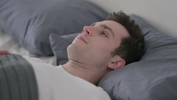 Worried Man Awake in Bed Thinking Close Up