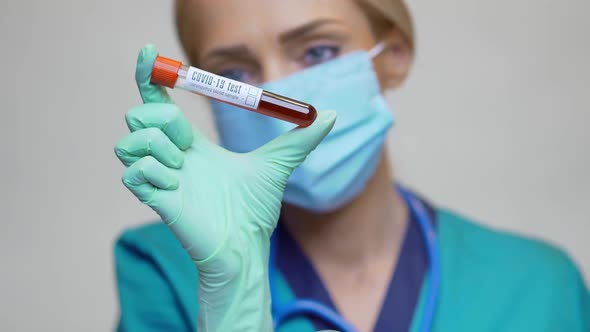 Medical Doctor Nurse Woman Wearing Protective Mask and Gloves - Holding COVID-19 Blood Test