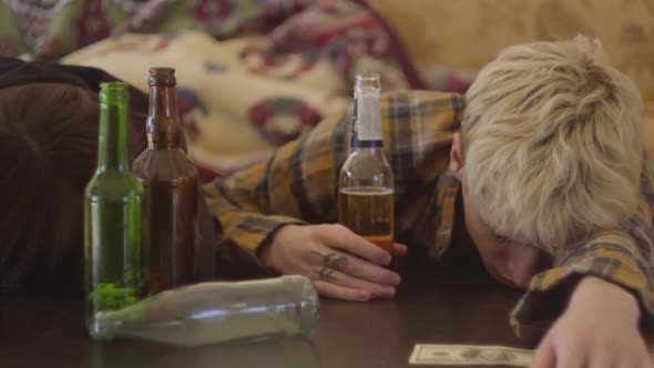 Young Bad Looking Friends Lying on the Table Near Empty Alcohol Bottles