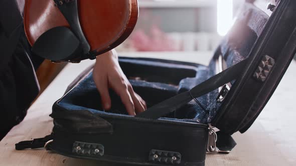 Young Woman Musician Putting the Violin in the Case