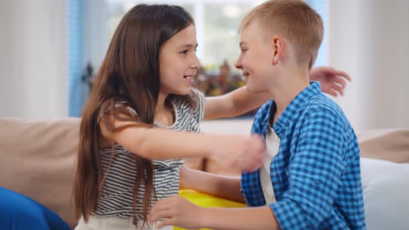 Portrait of Happy Brother and Sister Kids Hugging and Smiling Sitting on Couch