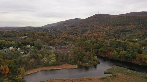 A high angle drone shot of the colorful fall foliage in upstate NY. The camera dolly in over to a st