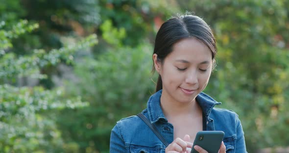 Woman work on mobile phone in city at park