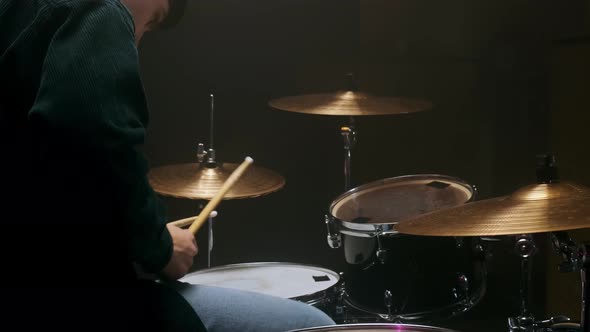 Drummer Playing the Drum Set in a Dark Room on a Black Background