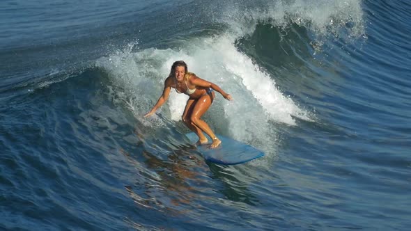 A young woman surfing in a bikini on a longboard surfboard.