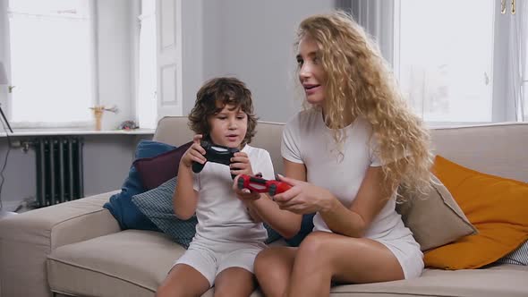 Blond Woman with Curly Hair Playing Video Game with Her Attractive Little Son