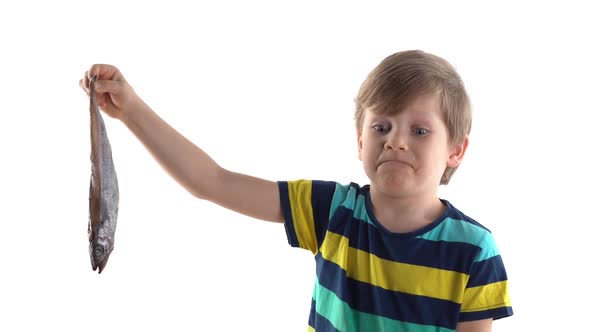 Boy Posing in Studio on a White Background with Raw Fish, Grimaces of Disgust