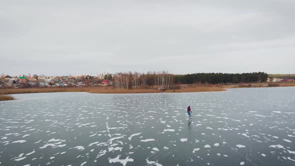 Aerial View. A Young Woman Is Skating on a Frozen Lake.