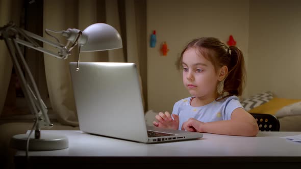 Little Girl Studying at an Online School on a Laptop