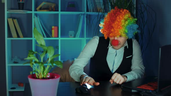 Young Man in Image of Clown Afraid of Computer Mouse in Office