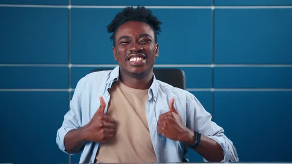 Young African American Student Dances Sits with Thumbs Up and Smiles Broadly