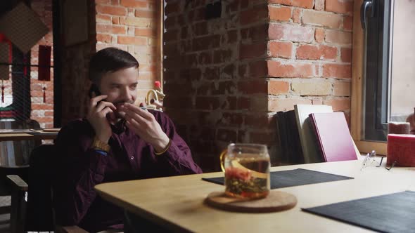 Young Businessman Sitting at Cafe and Talking on Phone When Having Tea Break