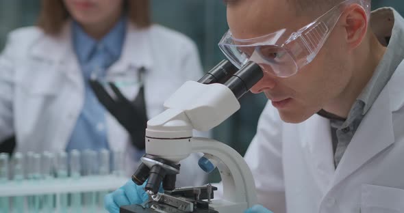 Microbiologist Is Researching Bacteria in Laboratory, Man Is Looking By Microscope, Biological