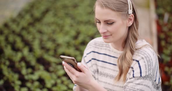 Agriculture - Female Gardener Using Mobile Phone in Greenhouse