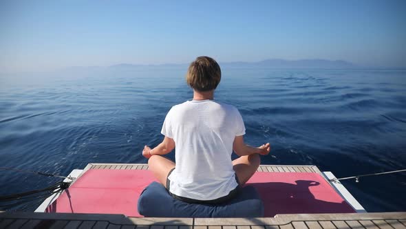 Young Woman Doing Yoga Meditation in Lotus Position on Yacht