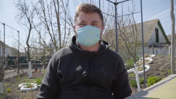 Portrait of Young Caucasian Man in Face Mask Looking at Camera and Agreeing. Brunette Guy Sitting