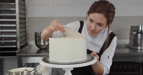 Professional Confectioner Evenly Applies Cream to the Holiday Cake