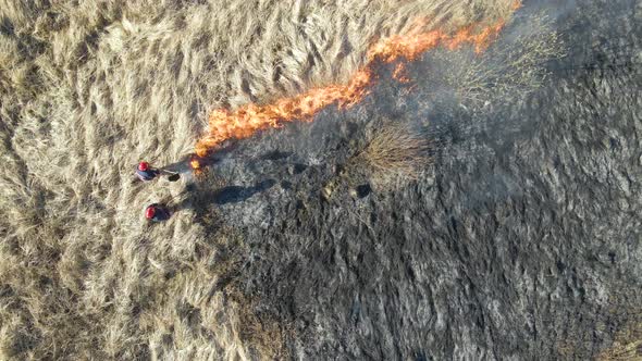 Aerial View of Firemen Extinguishing Grassland Field Burning with Red Fire During Dry Season