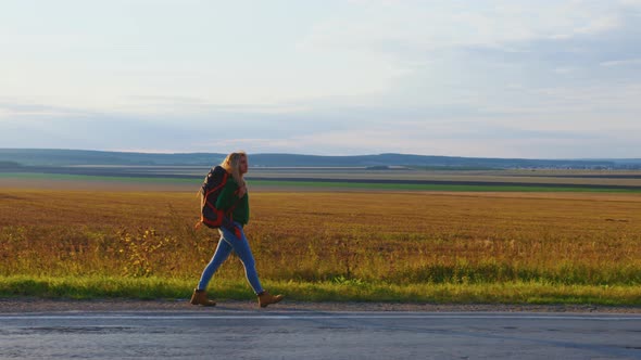 Girl Traveller with Backpack is Walking on Road